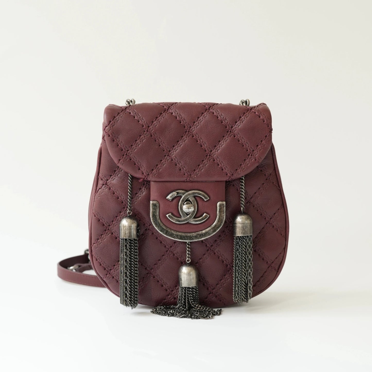 Front view of Chanel burgundy quilted leather mini crossbody bag with CC turnlock and metal tassel details