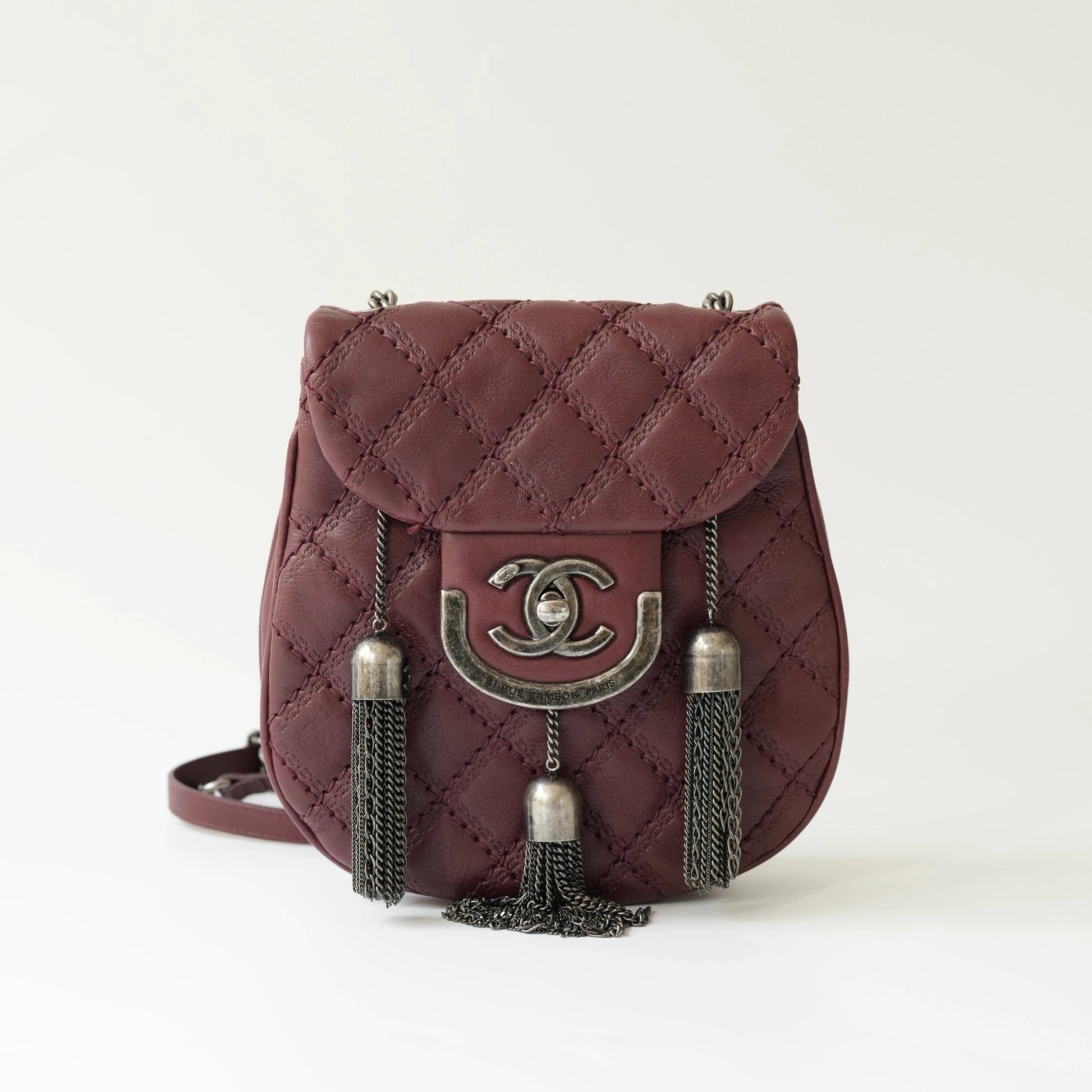 Front view of Chanel burgundy quilted leather mini crossbody bag with CC turnlock and metal tassel details