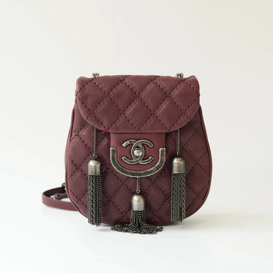 Front view of Chanel burgundy quilted leather mini crossbody bag with CC turnlock and metal tassel details