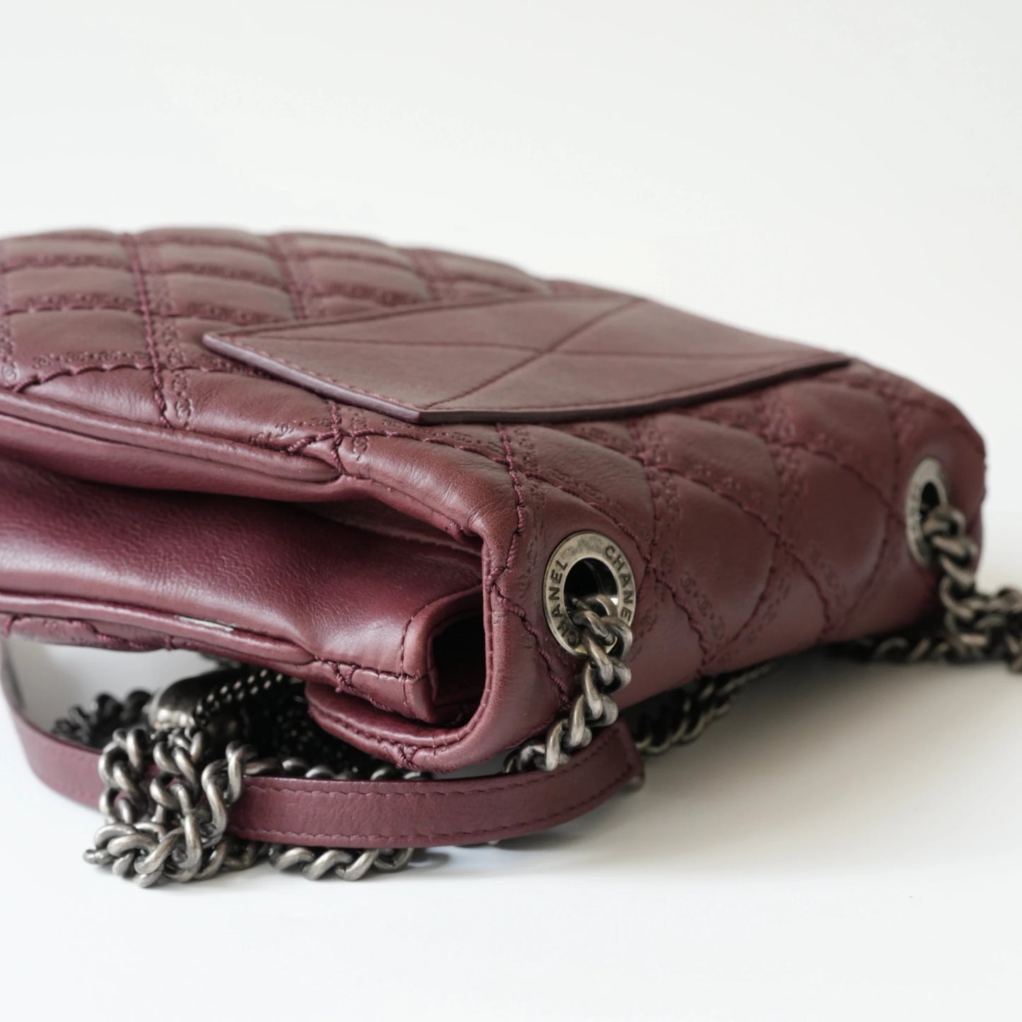Close-up of engraved CC turnlock and metal tassel detail on quilted leather bag