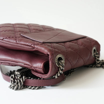 Close-up of engraved CC turnlock and metal tassel detail on quilted leather bag