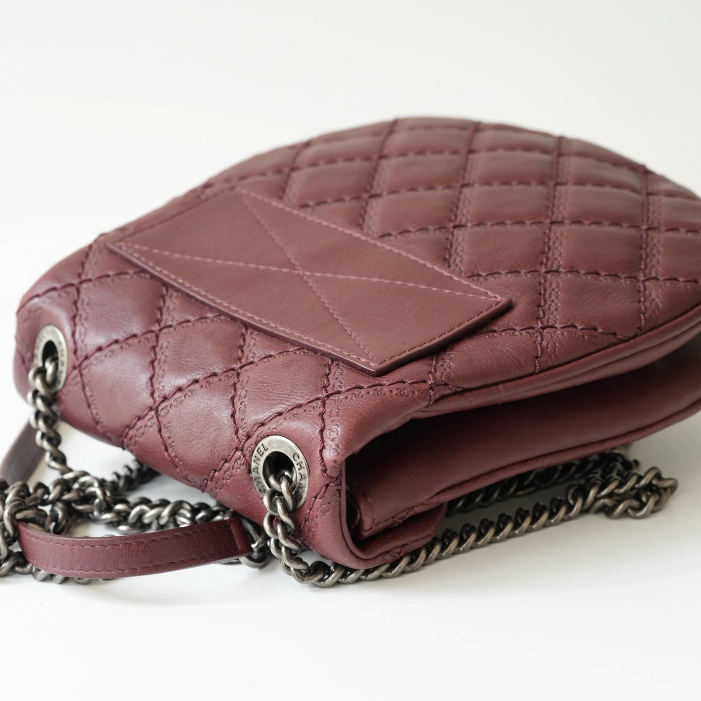 Close-up of engraved CC turnlock and metal tassel detail on quilted leather bag