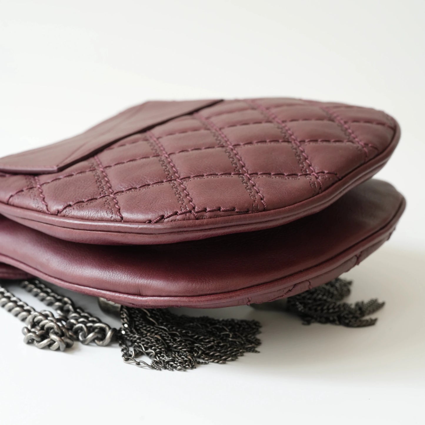 Close-up of engraved CC turnlock and metal tassel detail on quilted leather bag
