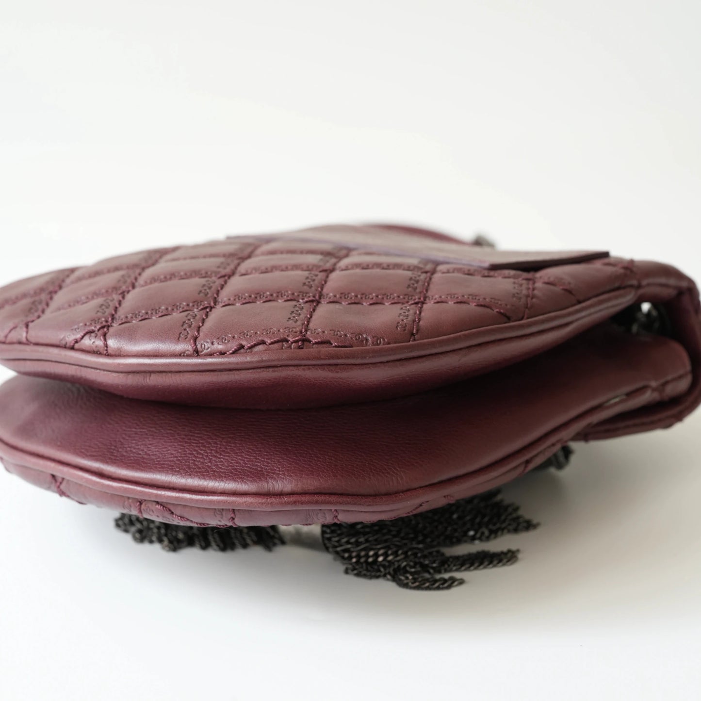 Close-up of engraved CC turnlock and metal tassel detail on quilted leather bag