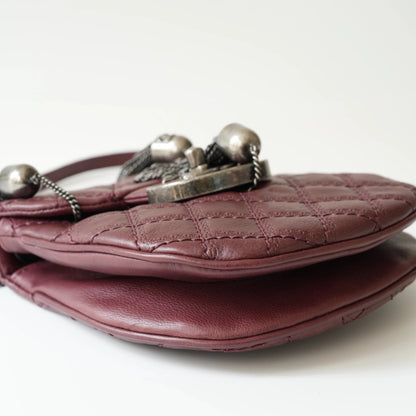 Close-up of engraved CC turnlock and metal tassel detail on quilted leather bag