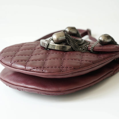 Close-up of engraved CC turnlock and metal tassel detail on quilted leather bag