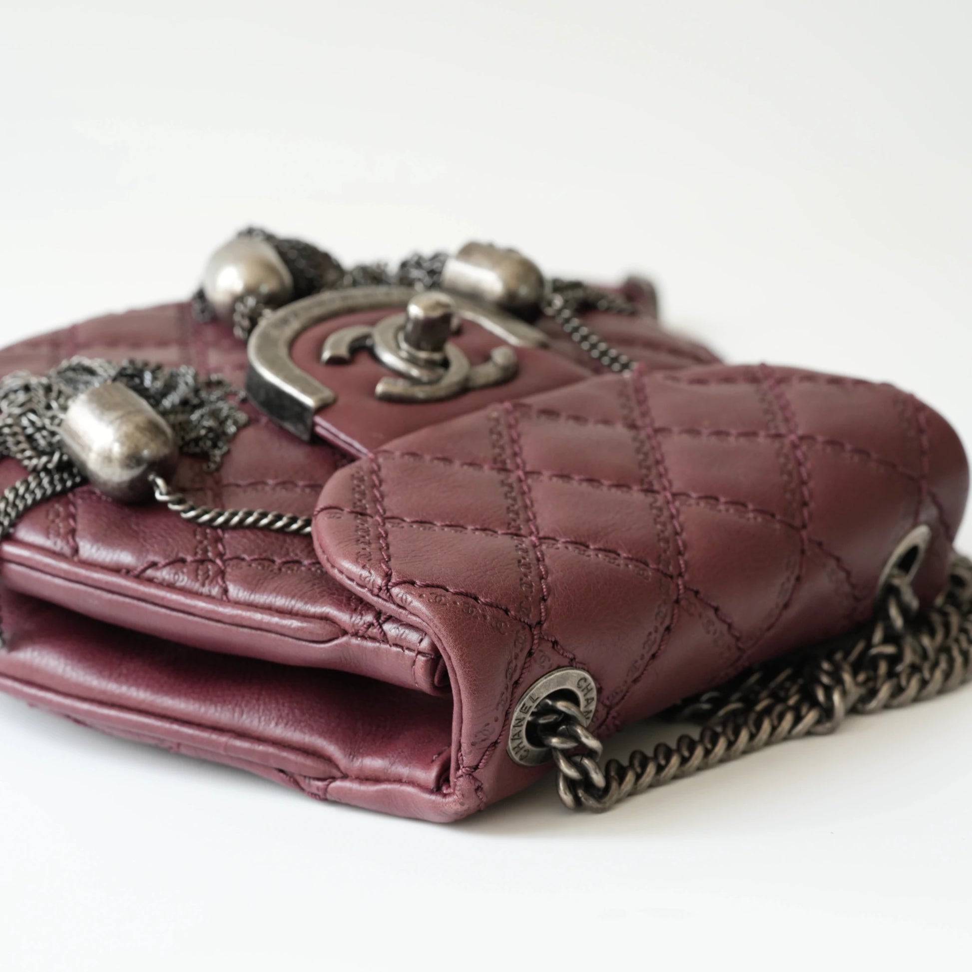Close-up of engraved CC turnlock and metal tassel detail on quilted leather bag