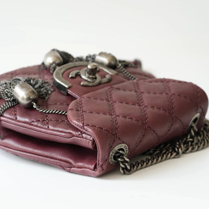 Close-up of engraved CC turnlock and metal tassel detail on quilted leather bag