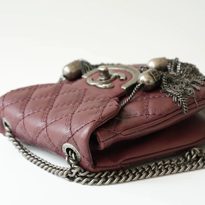Close-up of engraved CC turnlock and metal tassel detail on quilted leather bag
