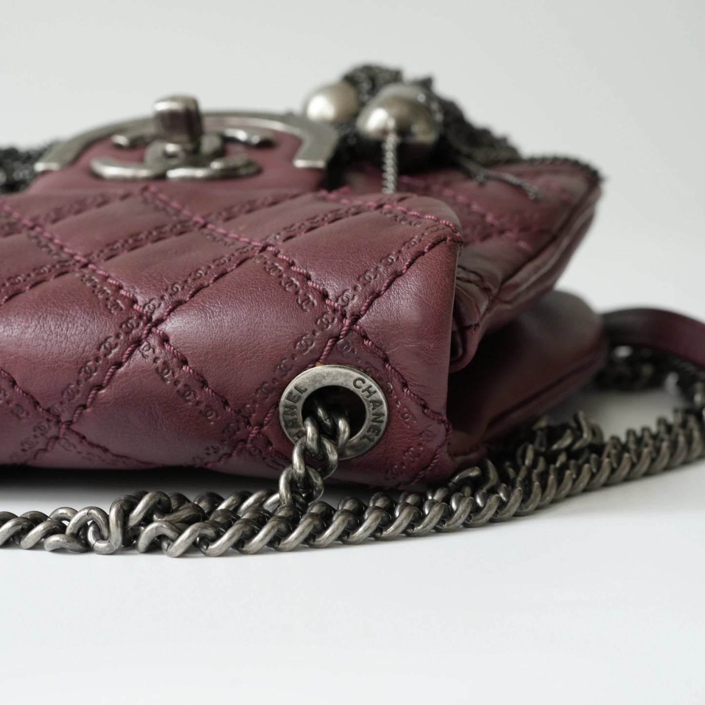 Close-up of engraved CC turnlock and metal tassel detail on quilted leather bag