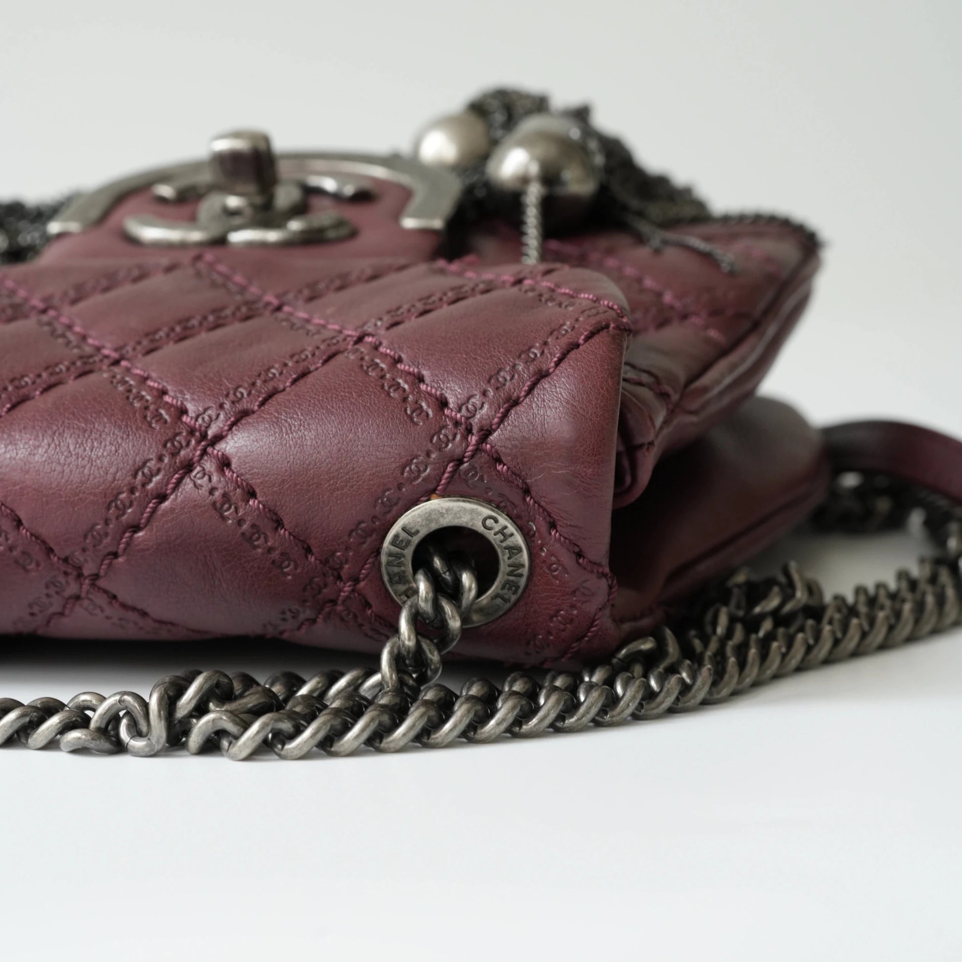 Close-up of engraved CC turnlock and metal tassel detail on quilted leather bag