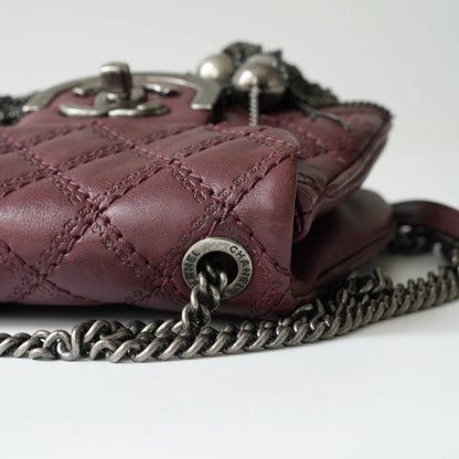 Close-up of engraved CC turnlock and metal tassel detail on quilted leather bag