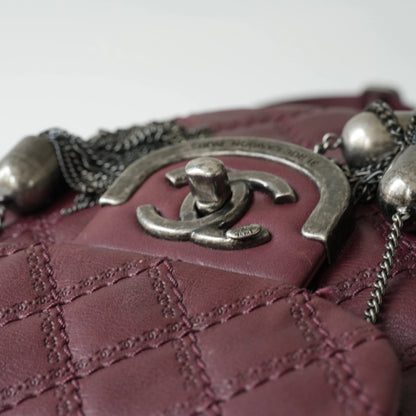 Close-up of engraved CC turnlock and metal tassel detail on quilted leather bag