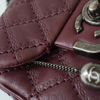 Close-up of engraved CC turnlock and metal tassel detail on quilted leather bag