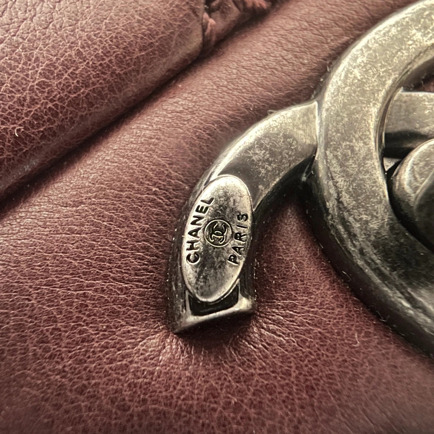 Close-up of engraved CC turnlock and metal tassel detail on quilted leather bag
