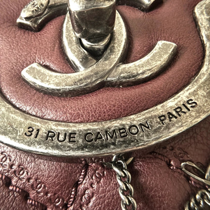 Close-up of engraved CC turnlock and metal tassel detail on quilted leather bag
