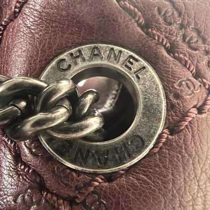 Close-up of engraved CC turnlock and metal tassel detail on quilted leather bag