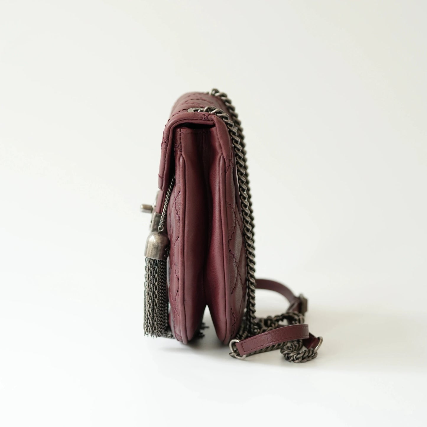 Side view of Chanel tassel mini bag showing slim profile and adjustable leather strap