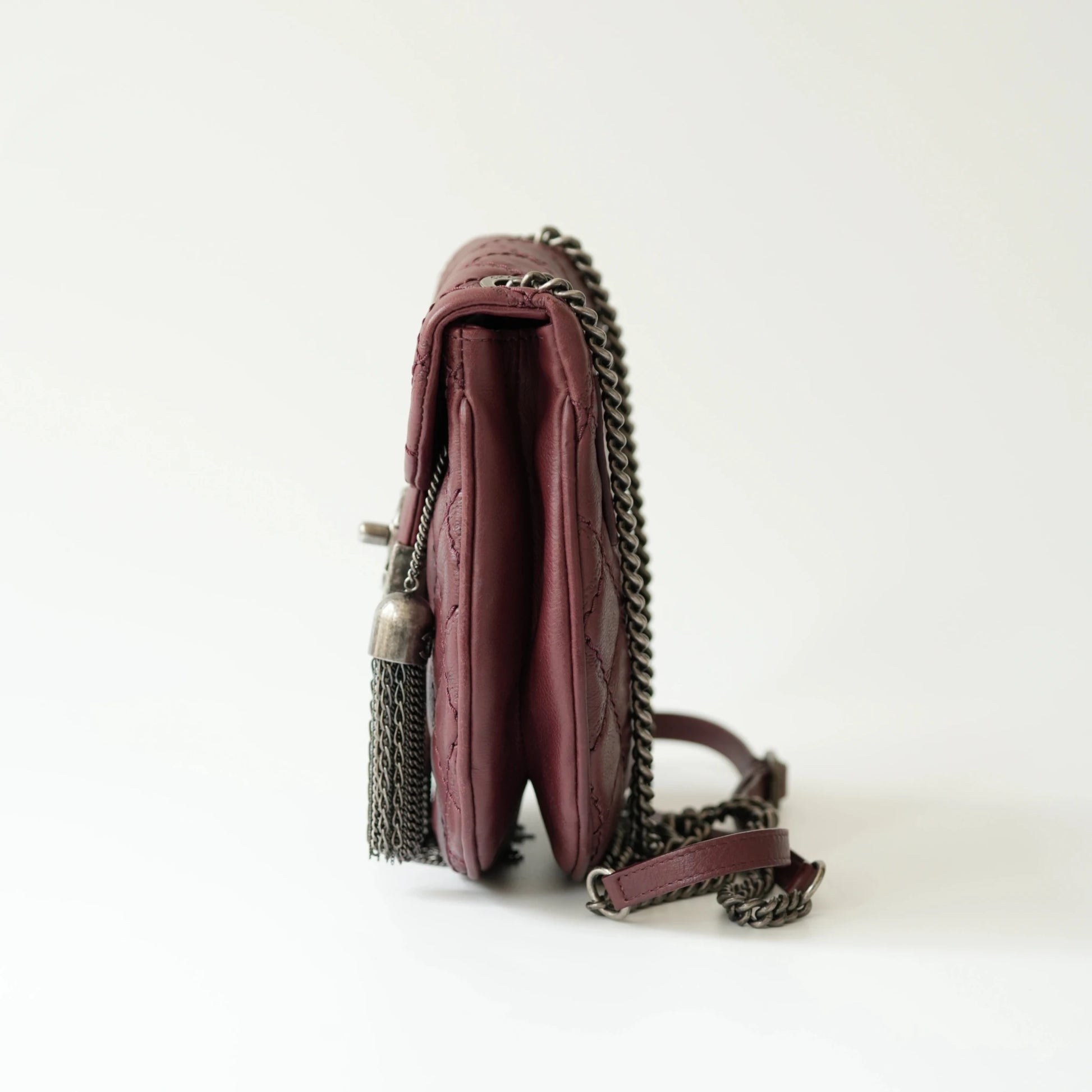 Side view of Chanel tassel mini bag showing slim profile and adjustable leather strap