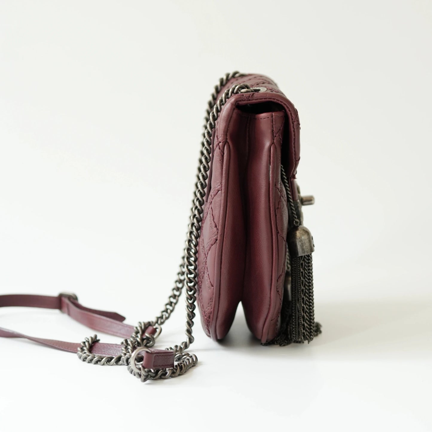 Side view of Chanel tassel mini bag showing slim profile and adjustable leather strap