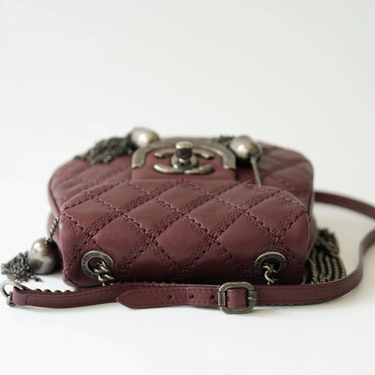 Top view of Chanel burgundy quilted bag showcasing flap closure and tassel ornaments