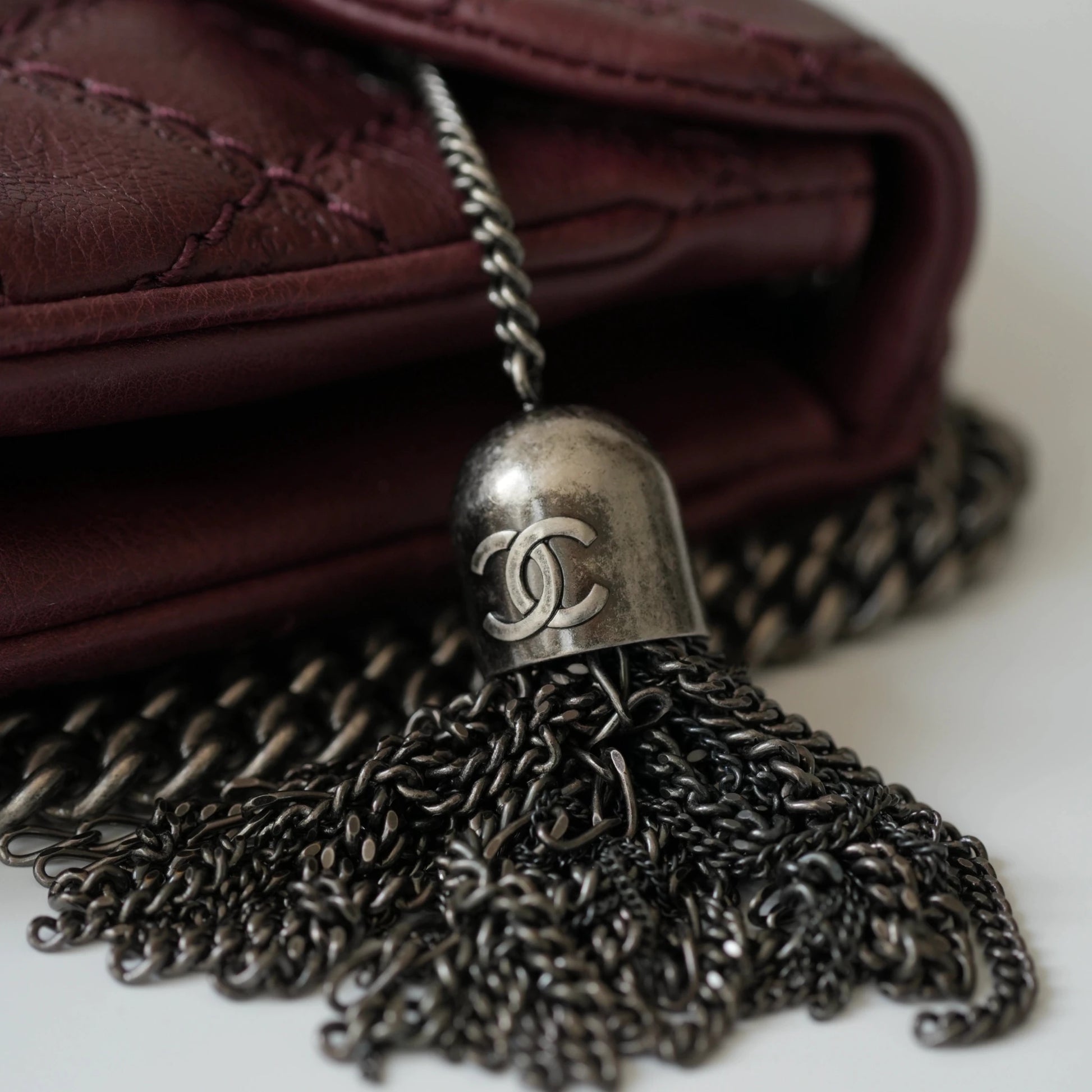 Close-up of engraved CC turnlock and metal tassel detail on quilted leather bag
