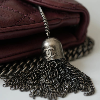 Close-up of engraved CC turnlock and metal tassel detail on quilted leather bag