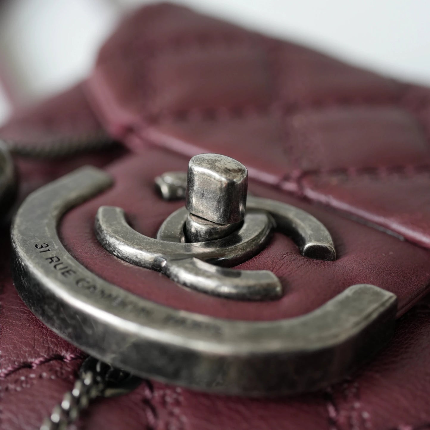 Close-up of engraved CC turnlock and metal tassel detail on quilted leather bag