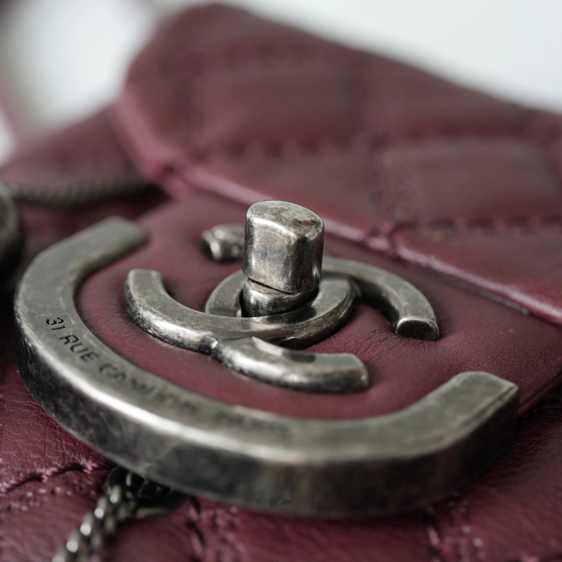 Close-up of engraved CC turnlock and metal tassel detail on quilted leather bag