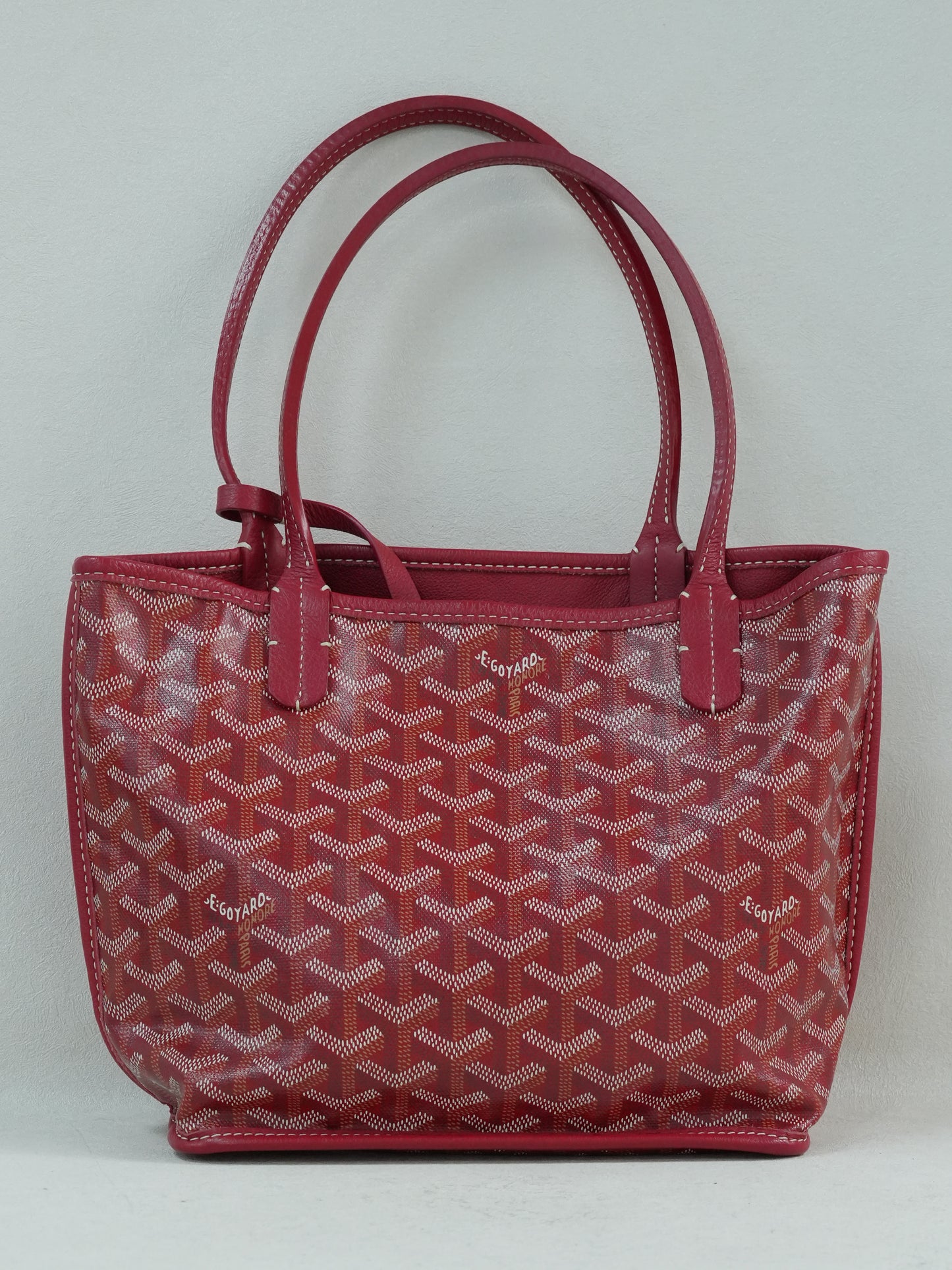 Back view of the red Goyardine herringbone canvas mini reversible tote bag, featuring calfskin trim and double handles.