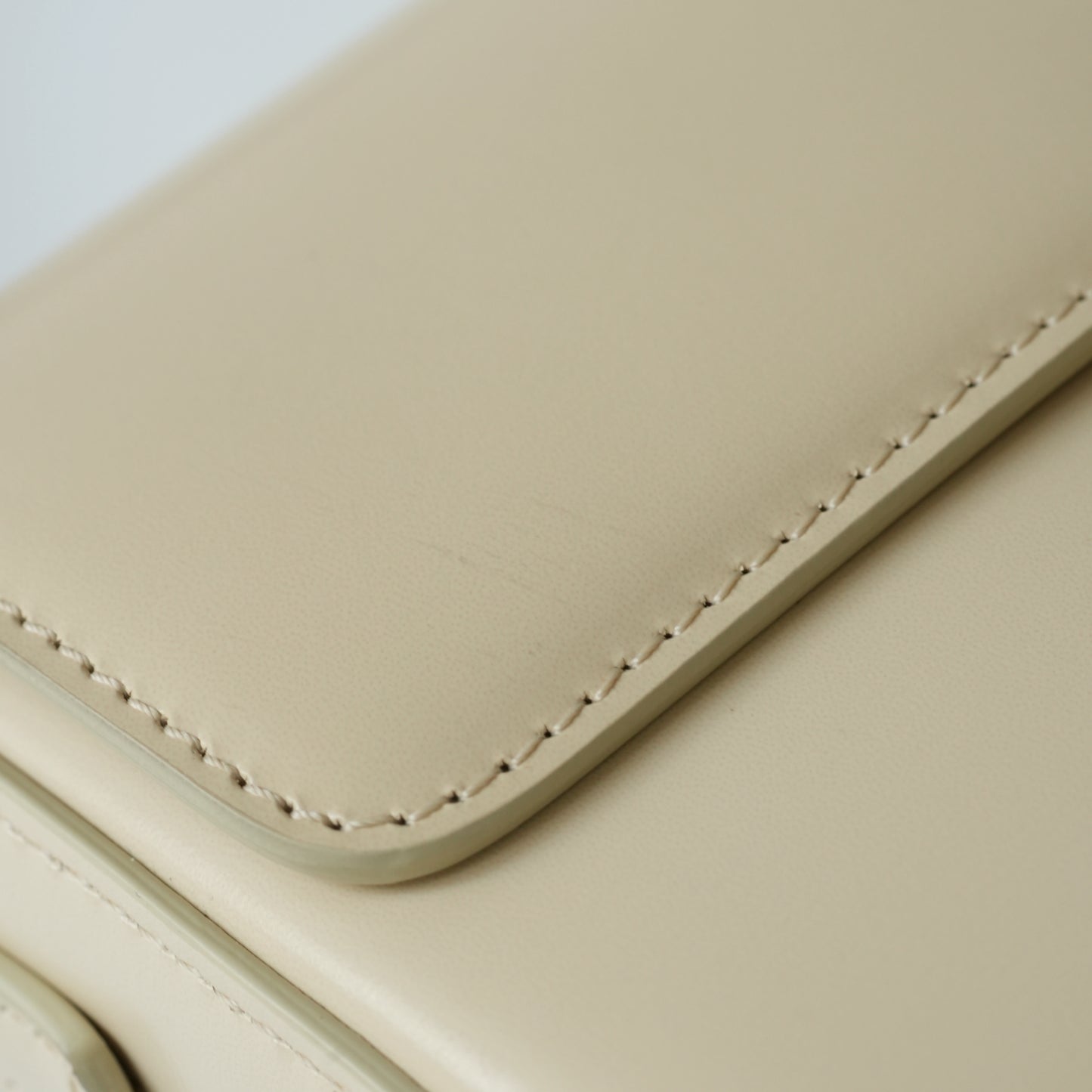 Detail view of gold Triomphe clasp and precise leather stitching