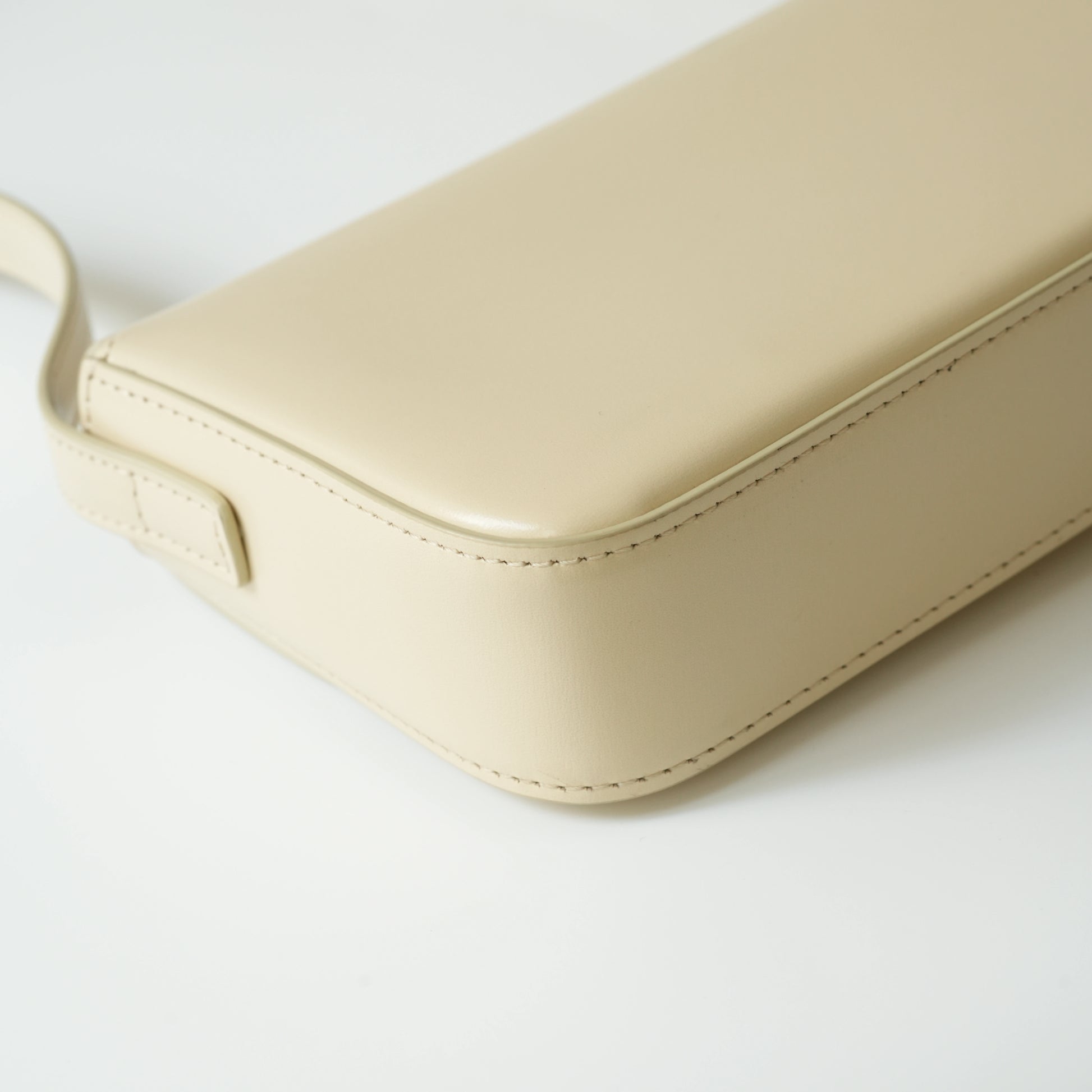Detail view of gold Triomphe clasp and precise leather stitching