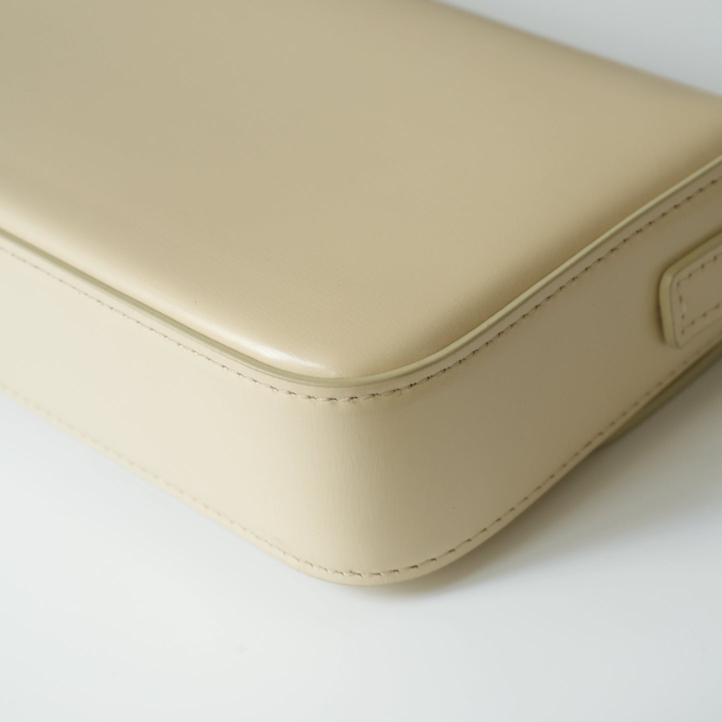 Detail view of gold Triomphe clasp and precise leather stitching