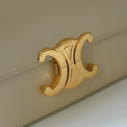 Detail view of gold Triomphe clasp and precise leather stitching