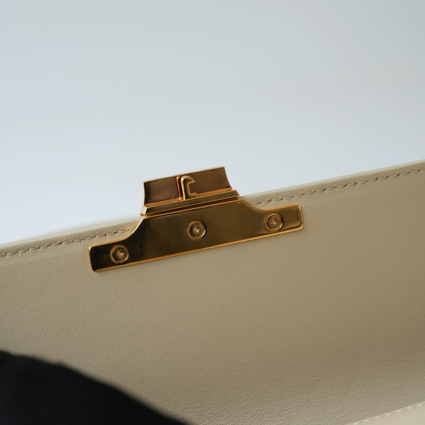 Detail view of gold Triomphe clasp and precise leather stitching