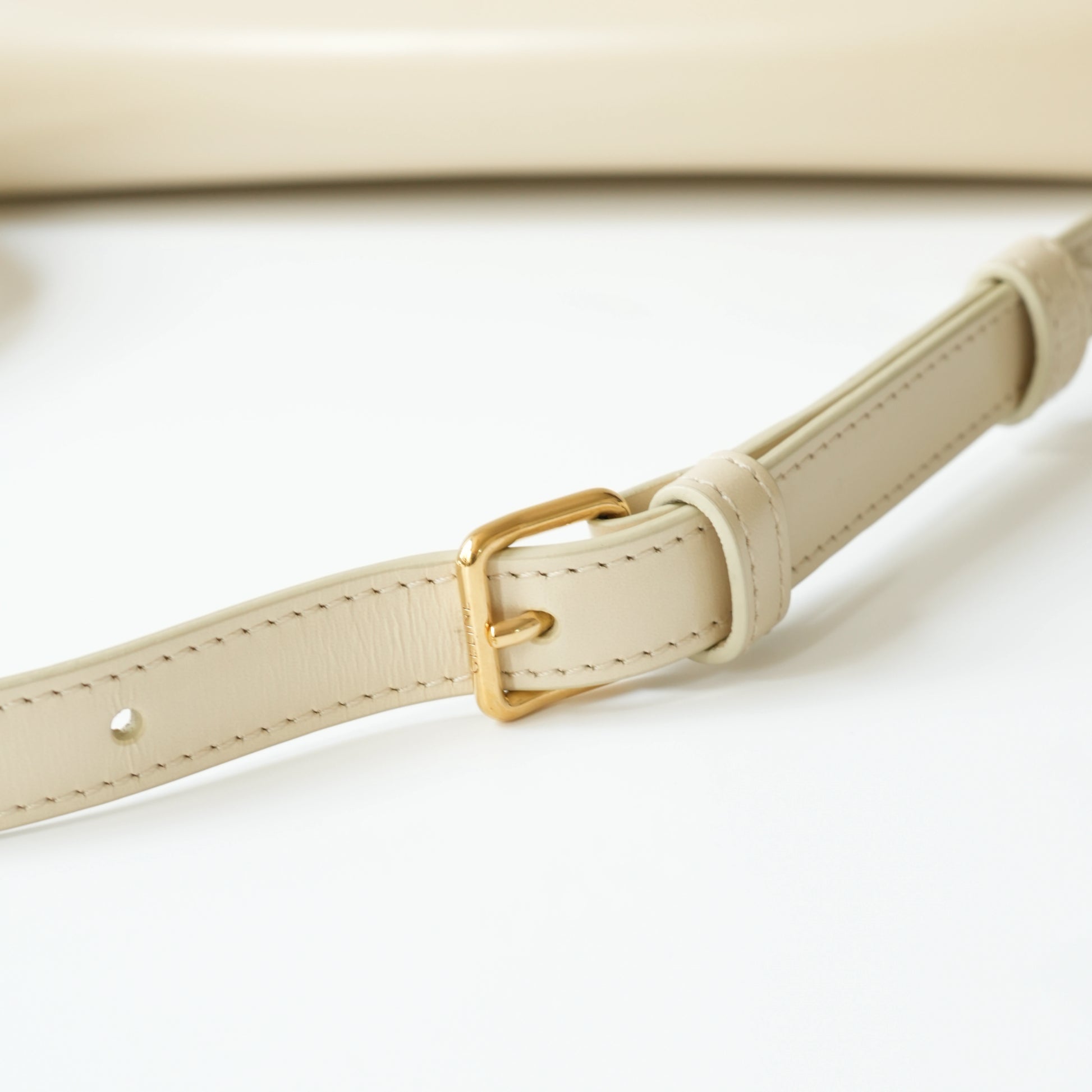 Detail view of gold Triomphe clasp and precise leather stitching