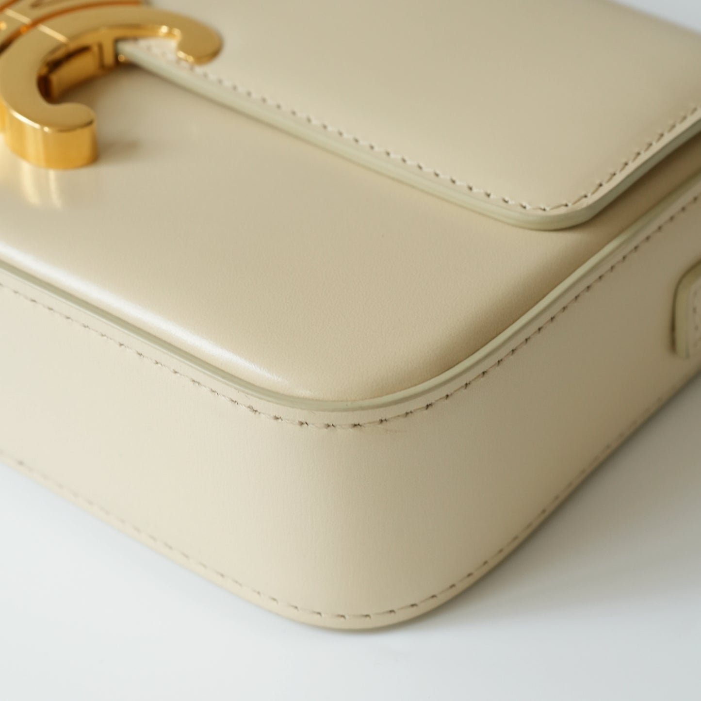 Detail view of gold Triomphe clasp and precise leather stitching