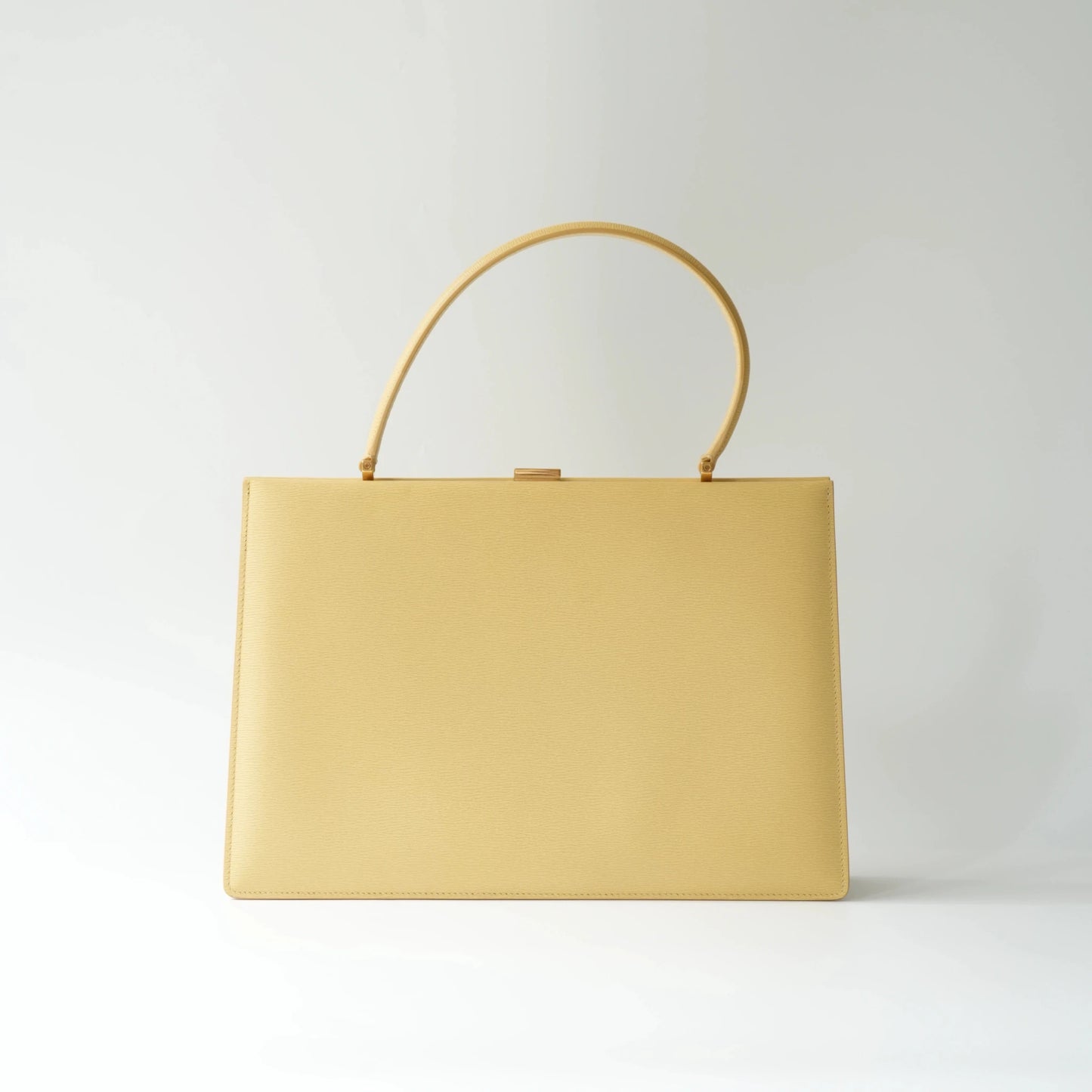 Front view of Celine yellow leather clasp top handle bag with sleek structured minimalist silhouette