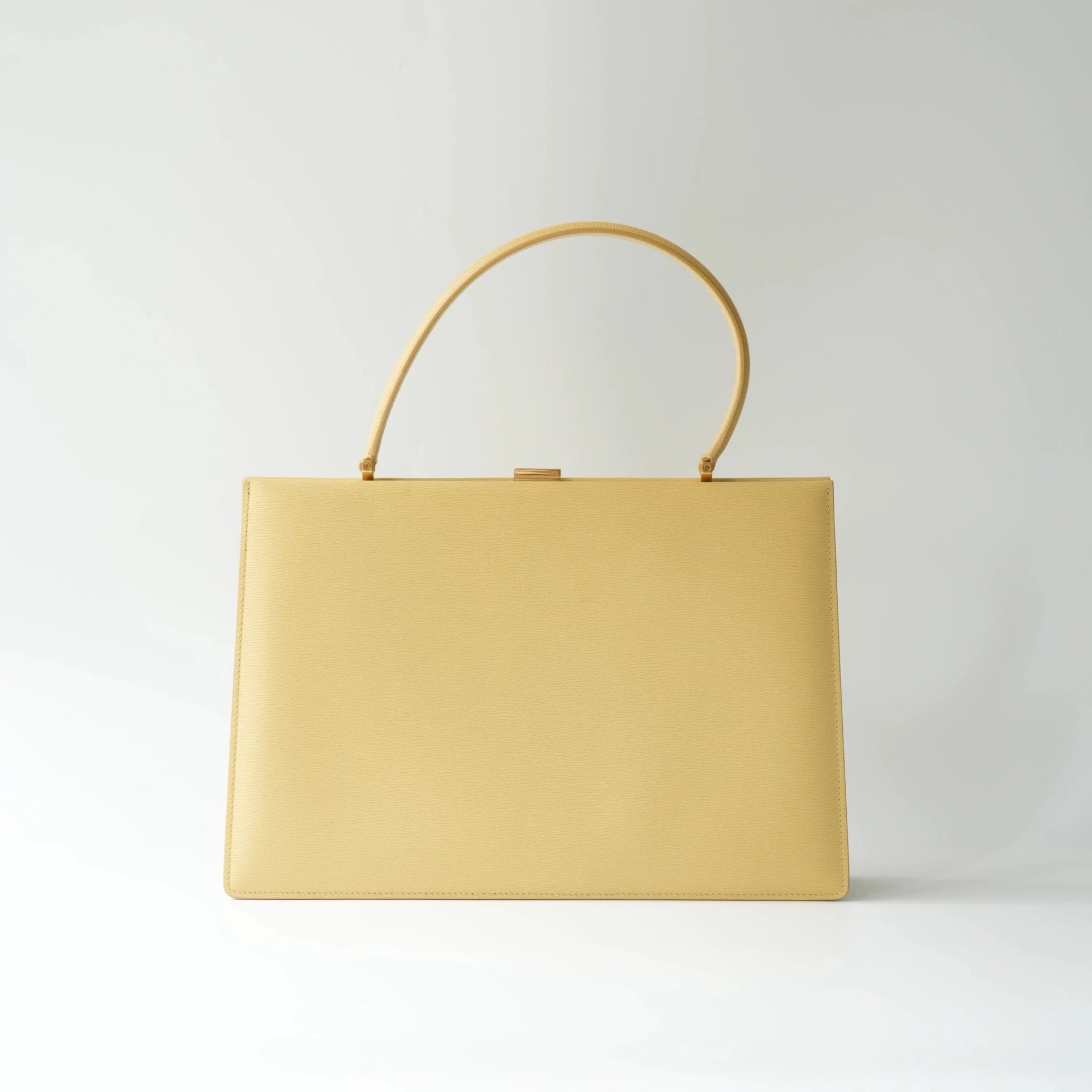Front view of Celine yellow leather clasp top handle bag with sleek structured minimalist silhouette