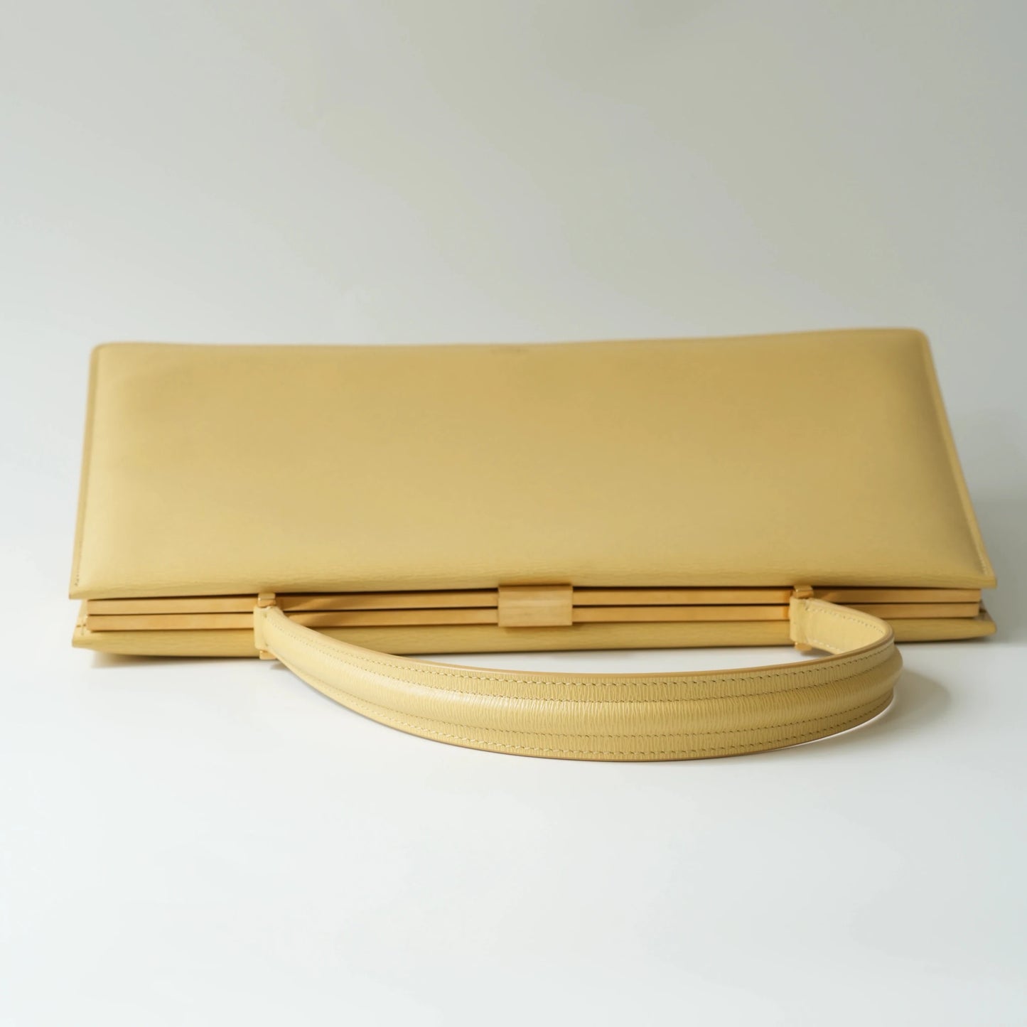 Top view of Celine yellow leather clasp top handle bag with polished metal clasp closure