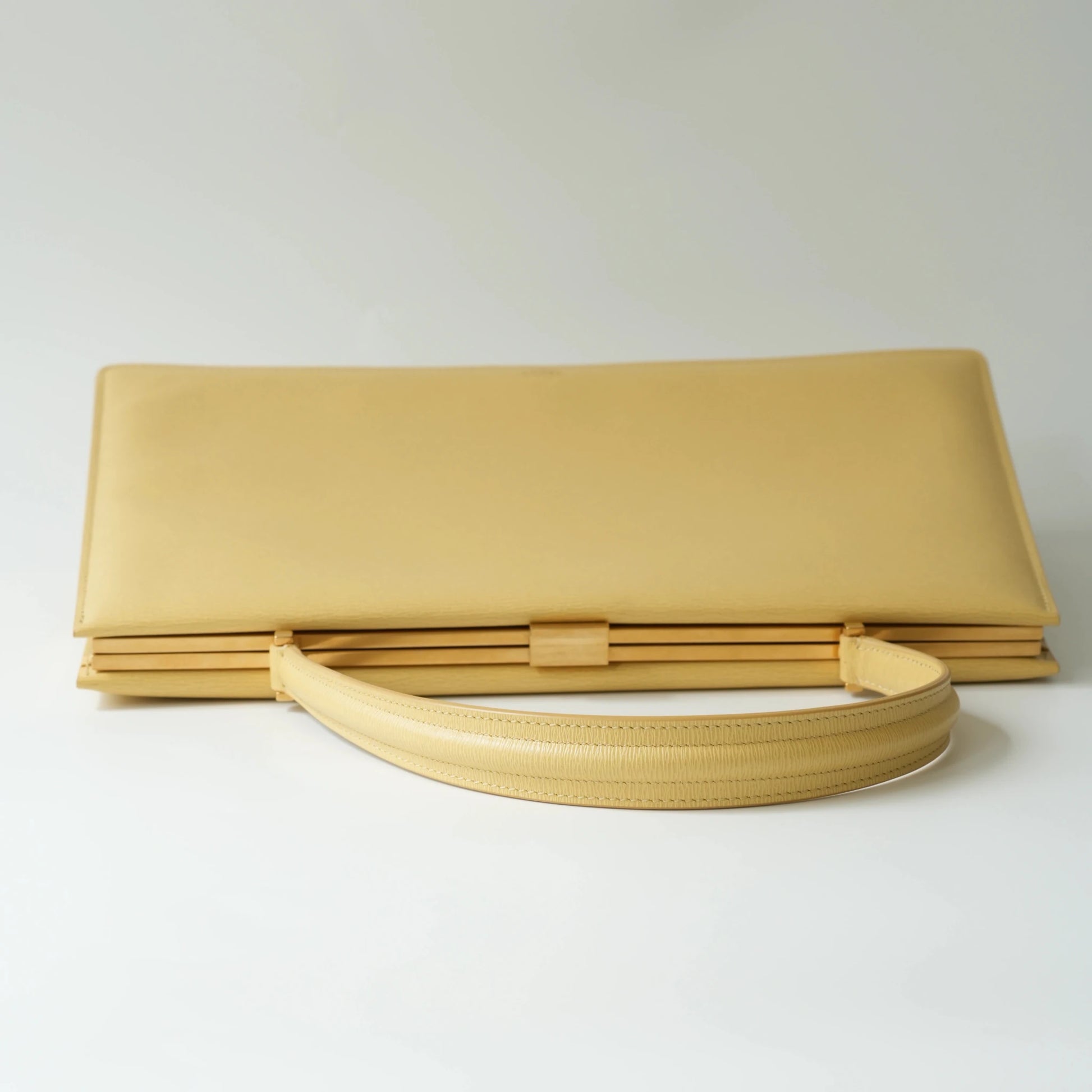 Top view of Celine yellow leather clasp top handle bag with polished metal clasp closure
