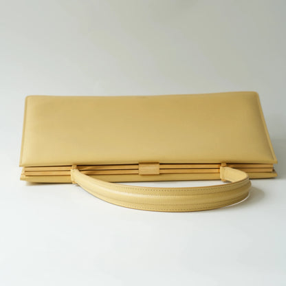 Top view of Celine yellow leather clasp top handle bag with polished metal clasp closure