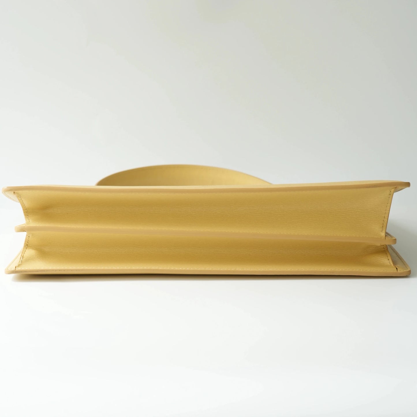 Bottom view of Celine yellow leather clasp bag with debossed Celine Paris logo at the base