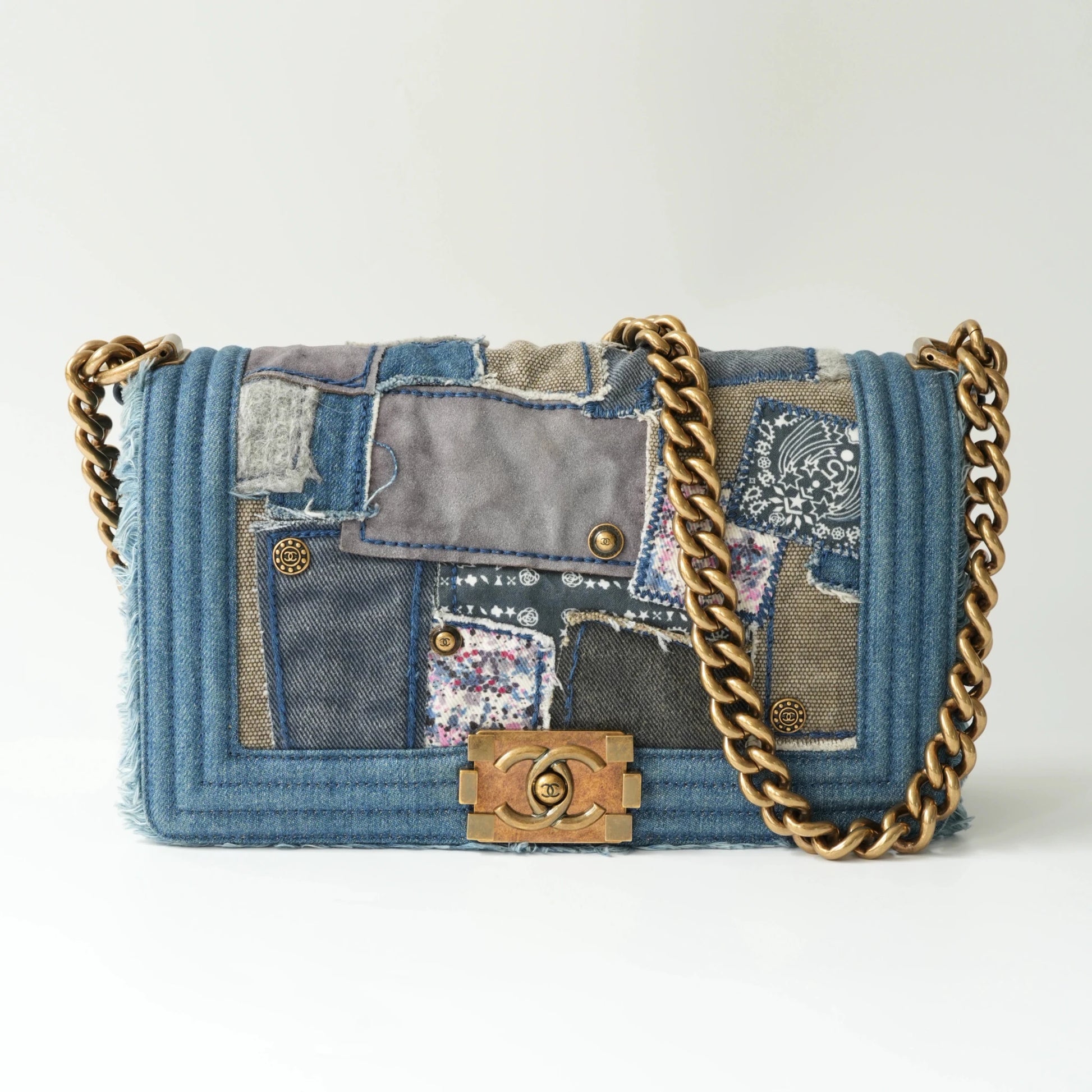 Front view of Chanel small Boy bag in patchwork denim with frayed edges and aged gold hardware