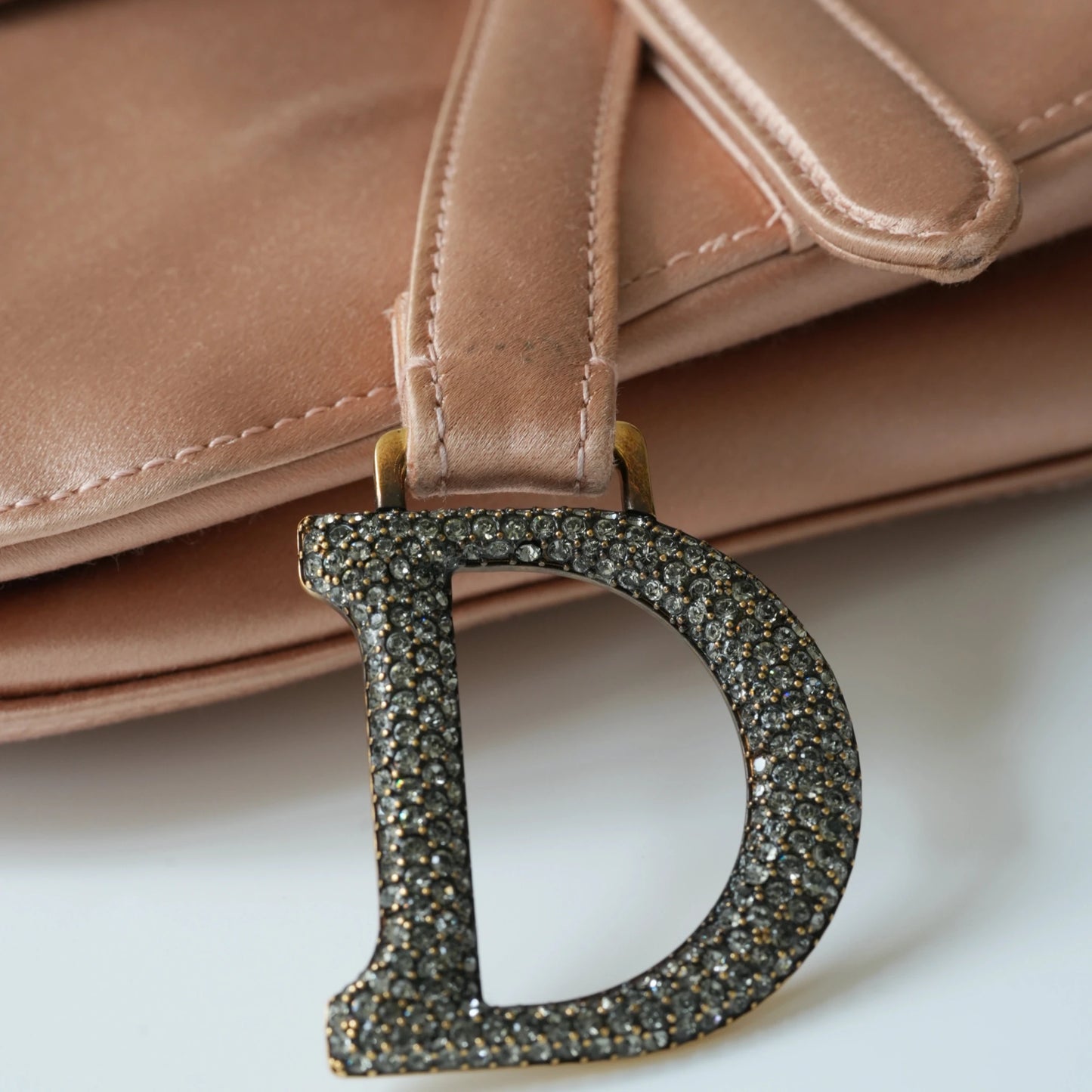 Detail view of crystal-embellished D stirrup charm and CD hardware