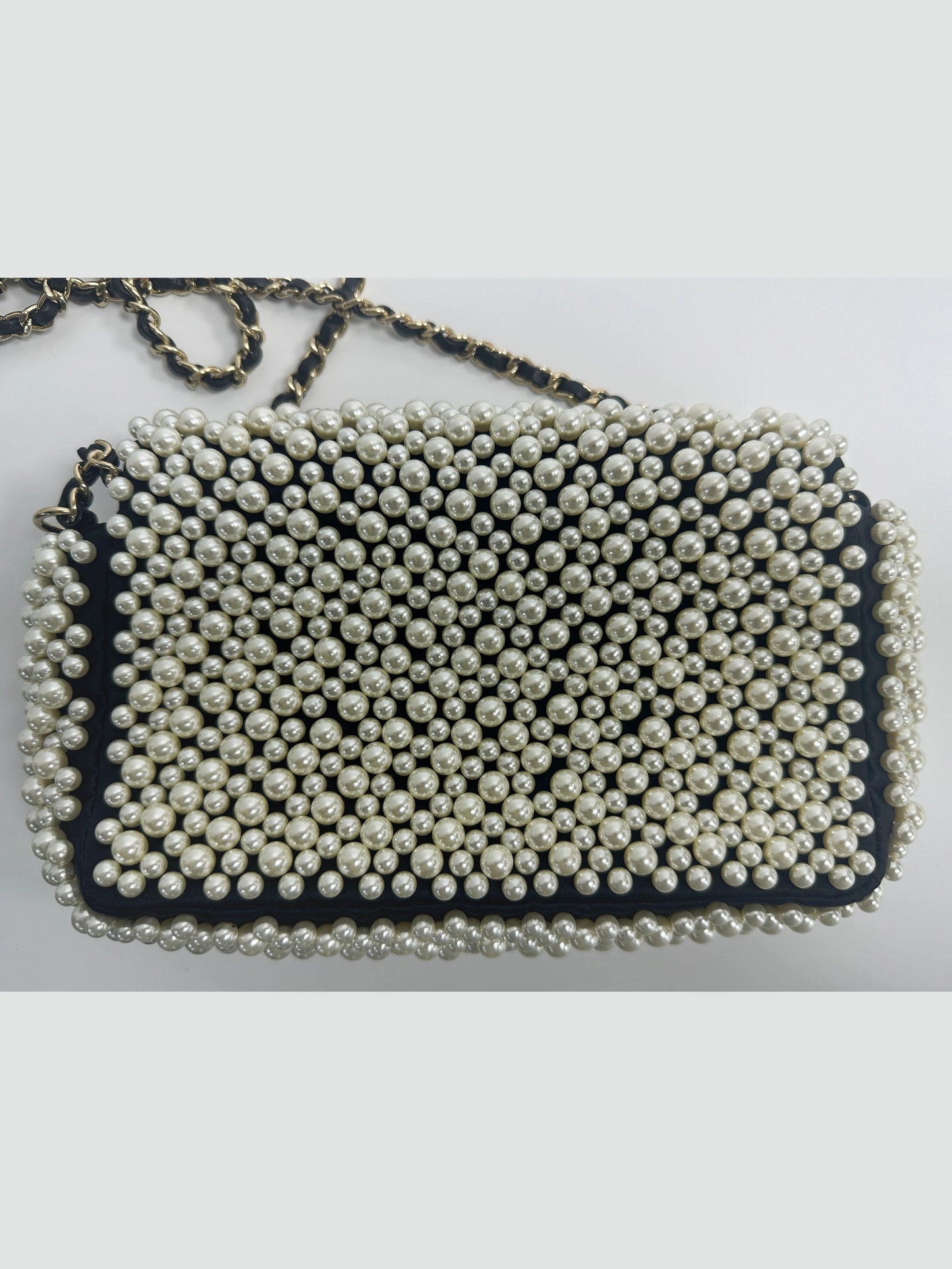 Back view of Chanel pearl embellished mini classic flap bag in black lambskin, neat pearl arrangement and smooth leather rear surface