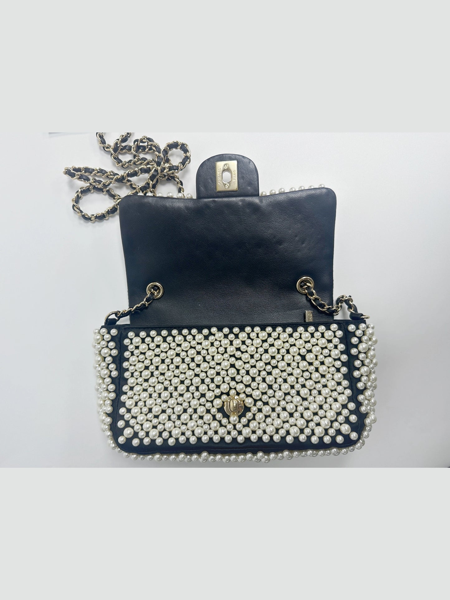 Interior view of Chanel pearl covered mini classic flap handbag, clean inner lambskin compartment with practical storage space