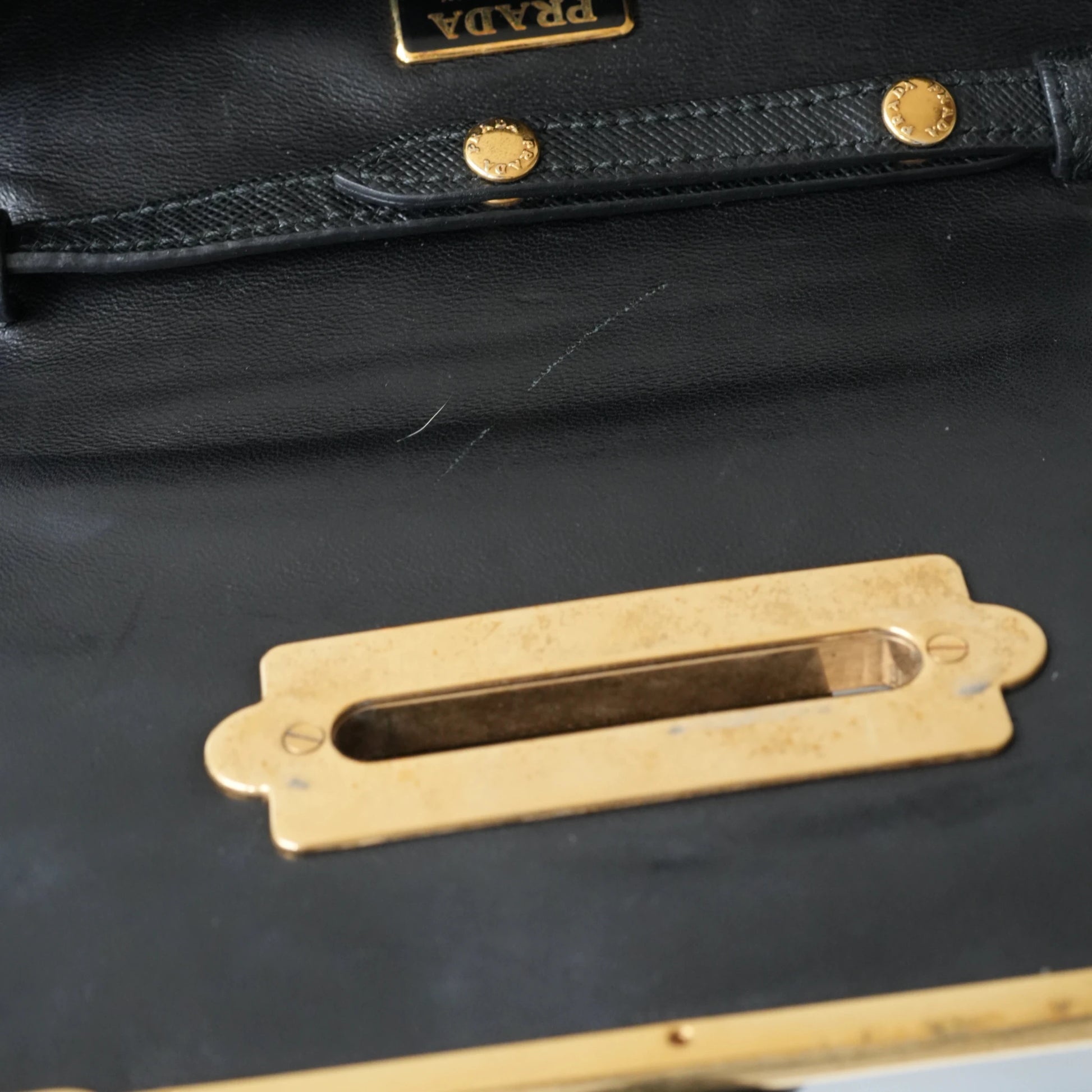 Detail view of gold Prada logo and celestial metal embellishments