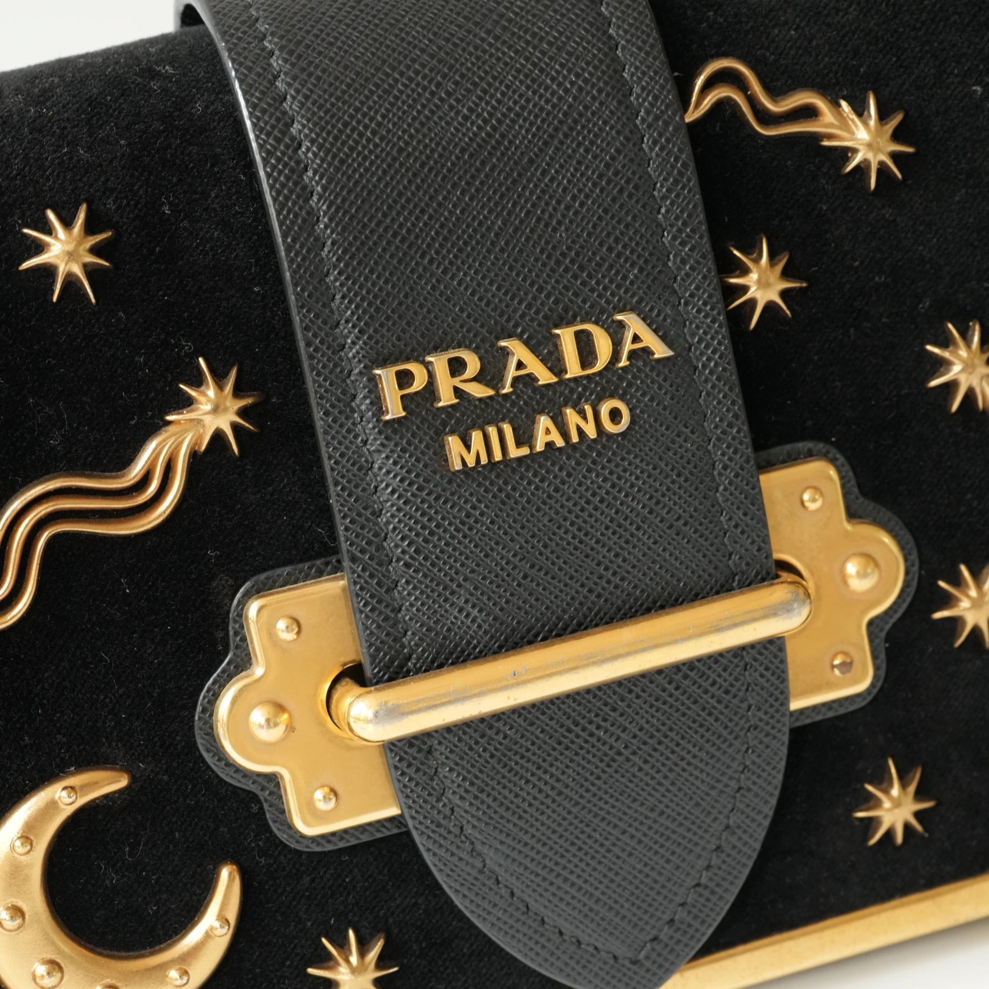 Detail view of gold Prada logo and celestial metal embellishments