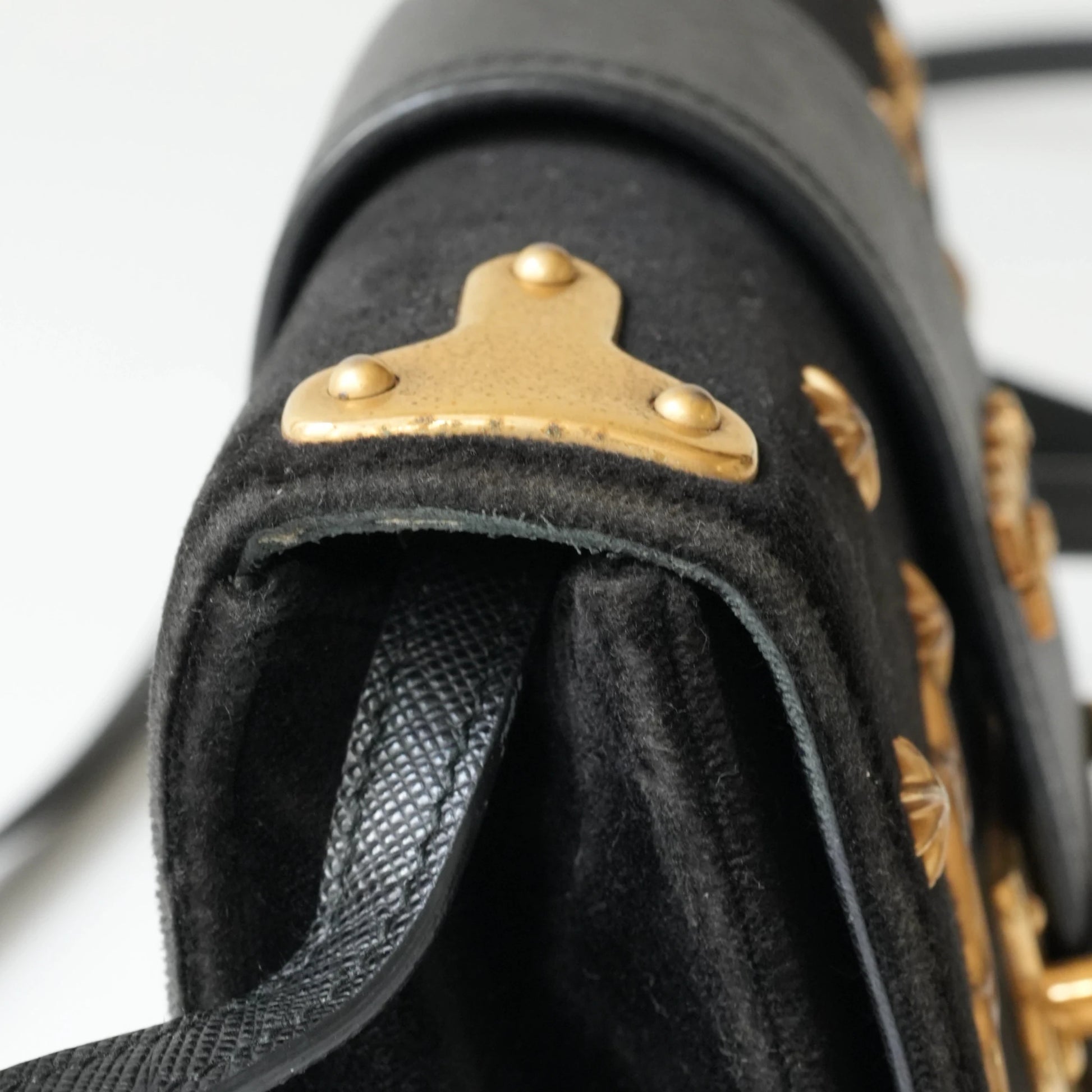 Detail view of gold Prada logo and celestial metal embellishments